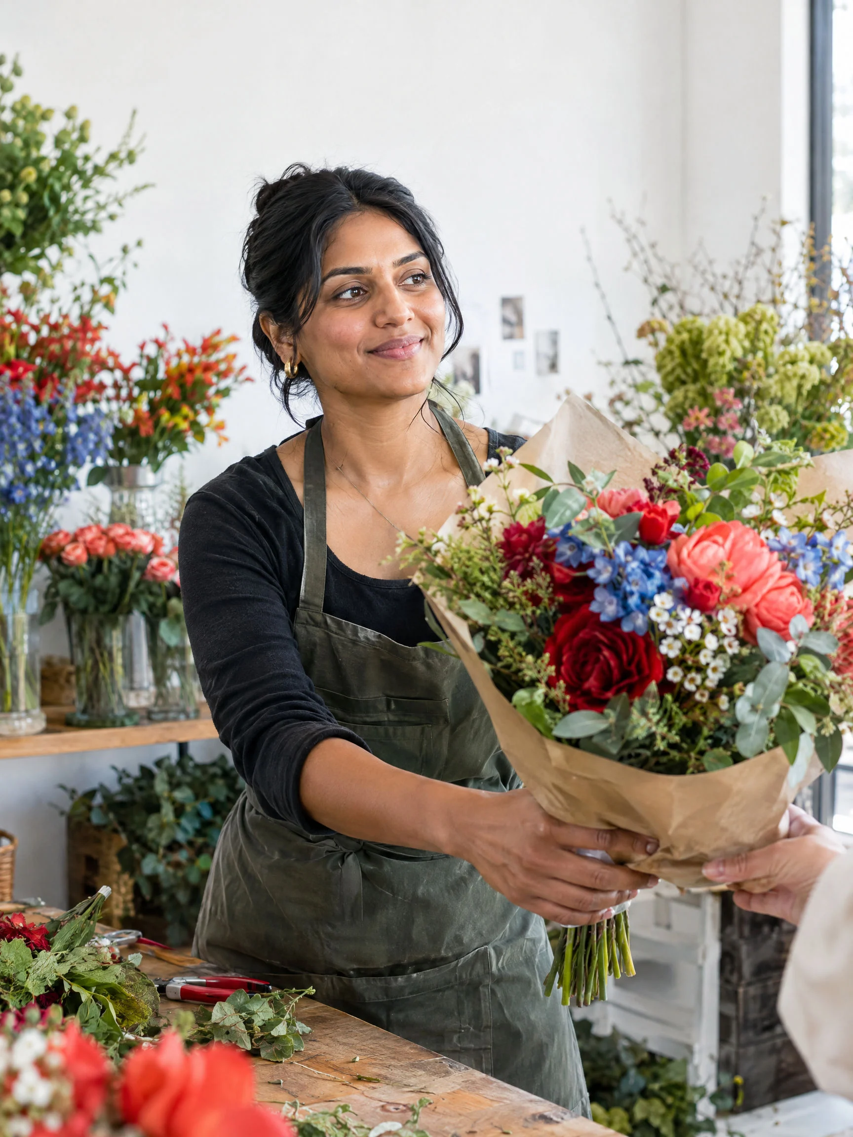 Florist handing a colorful bouquet to a customer in a bright shop